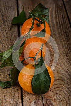 Three fresh tangerines with leaves on a wooden table