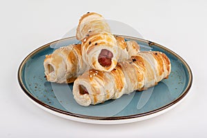 Three freshly baked sausages in batter on a plate.