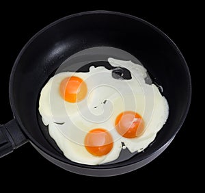Three fried eggs on the frying pan during cooking closeup