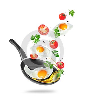 Three fried eggs with tomatoes and parsley fly out of the pan isolated on white background