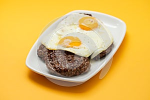 three fried ground meat with fried egg in white dish