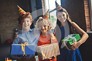 Three friends in bday hats holding presents
