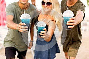 three friends cheerful company rest on a tropical beach and drink cocktails, very, magazine concept