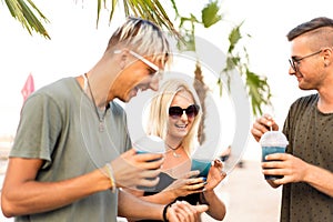 three friends cheerful company rest on a tropical beach and drink cocktails, very, magazine concept