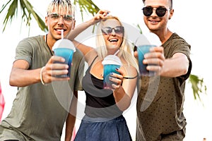 three friends cheerful company rest on a tropical beach and drink cocktails, very, magazine concept