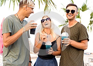 three friends cheerful company rest on a tropical beach and drink cocktails, very, magazine concept