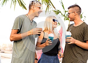 three friends cheerful company rest on a tropical beach and drink cocktails, very, magazine concept