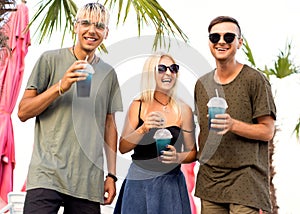 three friends cheerful company rest on a tropical beach and drink cocktails, very, magazine concept