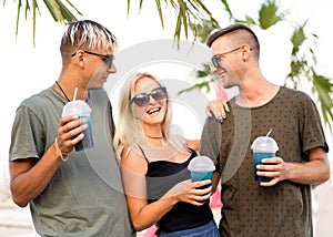 three friends cheerful company rest on a tropical beach and drink cocktails, very, magazine concept