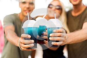 Three friends cheerful company rest on a tropical beach and drink cocktails, very, magazine concept