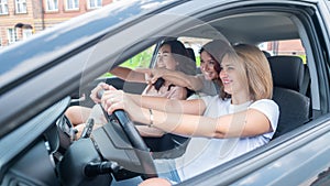 Three friends go on a trip. Caucasian women drive in a car and point fingers in surprise.