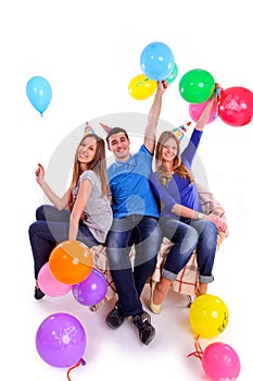 Three friends in hats with balloons sitting on the