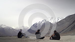 Three friends having a conversation while sitting on the ground in the mountains of ladakh. Having a conversation in solitude