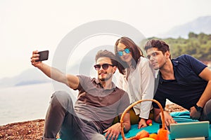 Three friends having fun at the beach, make selfie