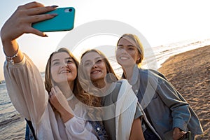 Three friends having fun on the beach, meeting friends. Young women