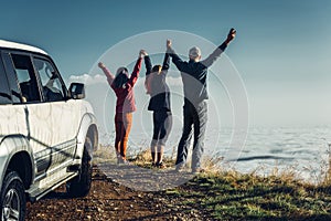 Three friends joined hands and raised their hands up, enjoying the view of Outdoor.Vacations Journey Concept