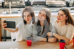Three friends making selfie drink coffee at cafe