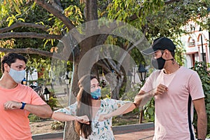 Three friends outdoors wearing face masks and respecting social distancing during a pandemic