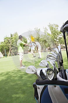 Three friends playing golf on the golf course, focus on the caddy
