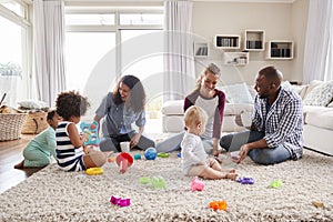 Three friends playing with toddlers on sitting room floor