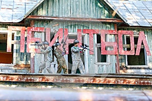 Three friends posing near giant sign with text paintball