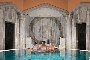 Three friends in swimming pool or thermal bath