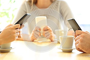 Three friends using their smart phones in a bar