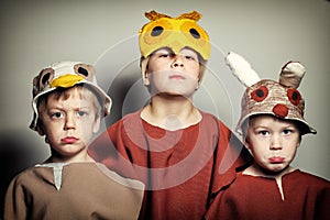 Three frown boys in masks of sparrow, owl and rabbit