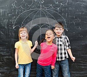 Three funny children with umbrella drawn on the blackboard