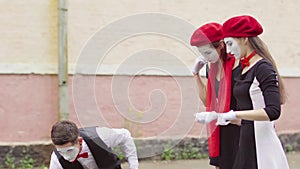 Three funny mimes play joking scenes on city street