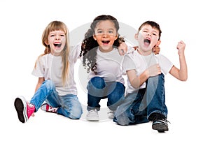 Three funny trendy children laugh sitting on the floor