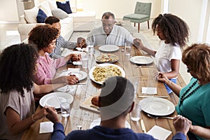 Three generation African American  family holding hands and saying grace at table before dinner,elevated view