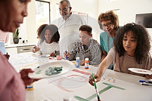 Three generation African American  family in the kitchen making a sign for a surprise party together, close up