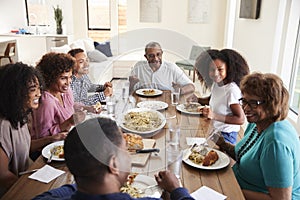 Three generation African American  family sitting at the table talking and eating dinner together, close up