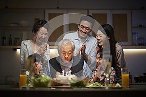 Three generation asian family celebrating grandpa`s birthday at home