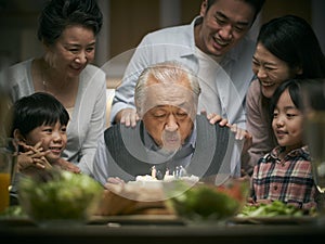 Three generation asian family celebrating grandpa`s birthday at home