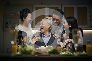 Three generation asian family celebrating grandpa`s birthday at home
