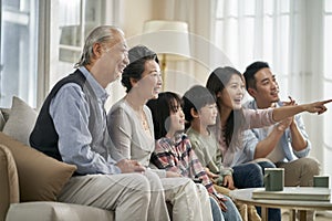 Three generation asian family watching tv together at home