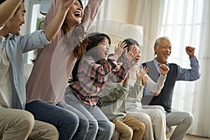 Three generation asian family watching soccer game telecast on TV