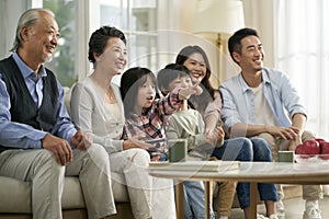 Three generation asian family watching tv together at home