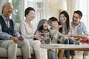 Three generation asian family watching tv together at home