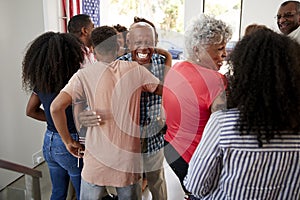 Three generation African American  family welcoming guests to their Independence Day party,back view