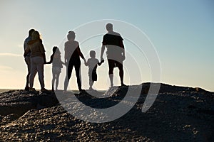 Three generation family on a beach holding hands, admiring view, full length, silhouette, back view photo