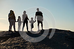 Three generation family on a beach holding hands, admiring view, full length, silhouette, back view