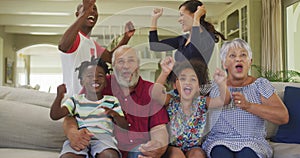 Three generation family cheering while watching TV at home