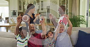 Three generation family cheering while watching TV at home