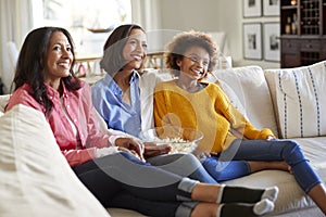 Three generation family female family group spending time together sitting on the sofa watching TV at home, selective focus