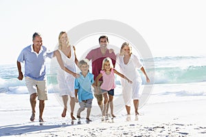 Three Generation Family On Holiday Running Along Beach