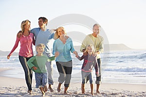 Three Generation Family On Holiday Running Along Beach