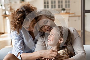 Three generation family little girl mom grandma tickle on sofa